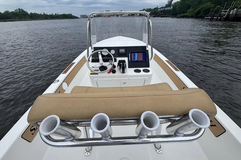Slide: The Image of 2025 Savannah 190 IS boat interior with steering wheel and navigation system on a calm river. - 8