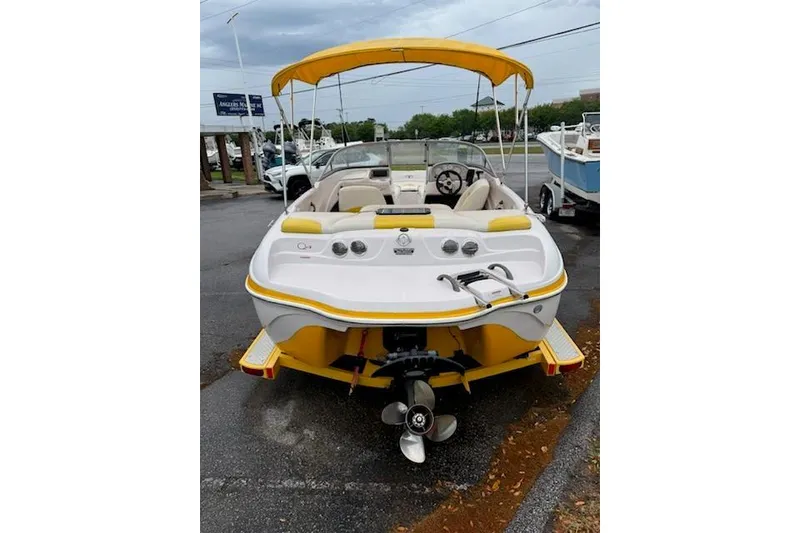 Slide: The Image of 2008 Tahoe Q4 SF boat with yellow canopy and seating, parked on wet pavement. - 3