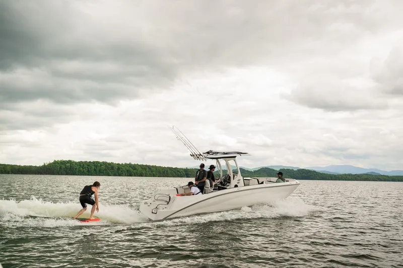 Slide: The Image of 2026 Yamaha Boats 252 FSH Sport towing a wakeboarder on a scenic lake. - 12