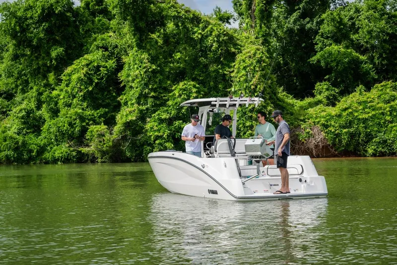 Slide: The Image of 2026 Yamaha Boats 252 FSH Sport on a serene lake with lush greenery. - 13