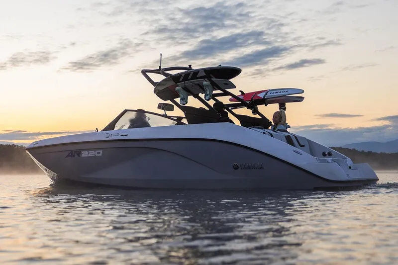 Slide: The Image of Manufacturer Provided Image: 2026 Yamaha Boats AR220 cruising at sunset with wakeboards on rack. - 8