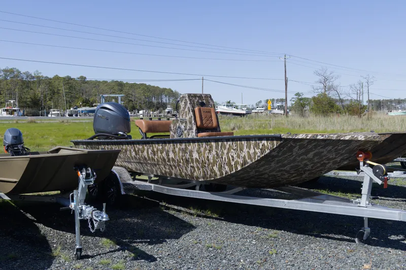 Slide: The Image of 2026 Avid 20 Rogue CC boat on trailer, camo design, parked outdoors. - 4