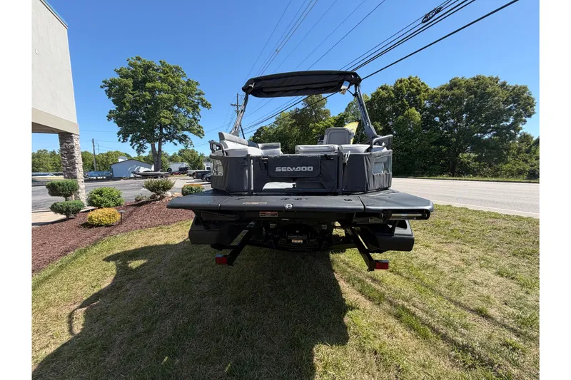 Slide: The Image of 2024 Sea-Doo Switch Sport 21 pontoon boat parked on grass, rear view. - 7