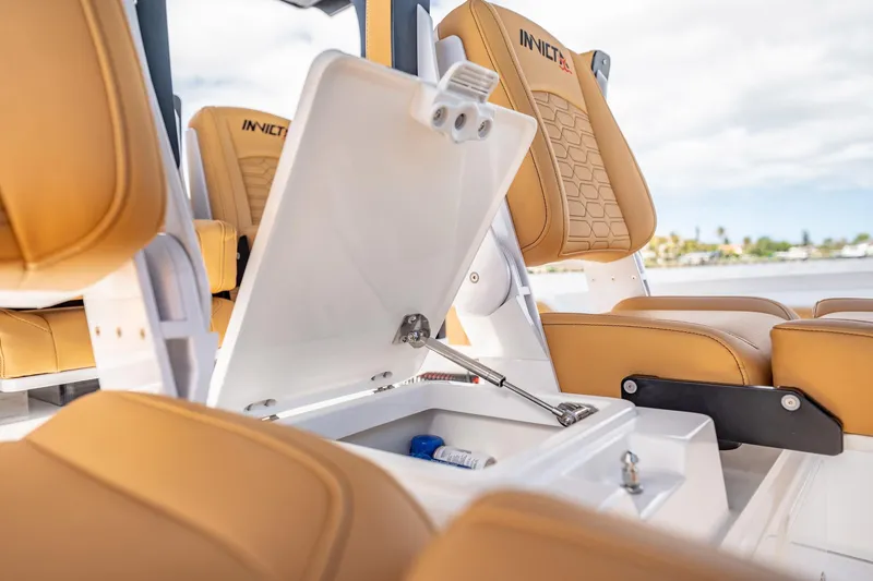 Slide: The Image of 2026 MVI Invicta 30OC boat interior with tan seats and open storage compartment. - 20