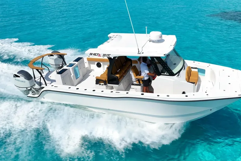 Slide: The Image of 2026 MVI Invicta 30OC boat cruising on clear turquoise water, showcasing sleek design and powerful engines. - 1
