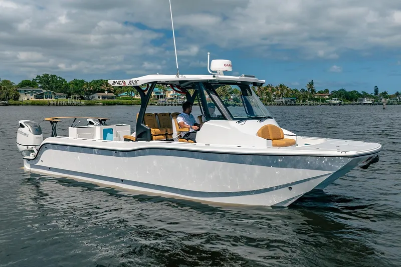 Slide: The Image of 2026 MVI Invicta 30OC boat cruising on a calm river under a cloudy sky. - 7