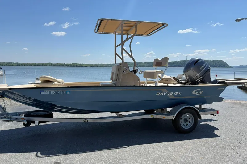 The Image of 2022 G3 Bay 18 GX boat on trailer by a scenic lake. - 1