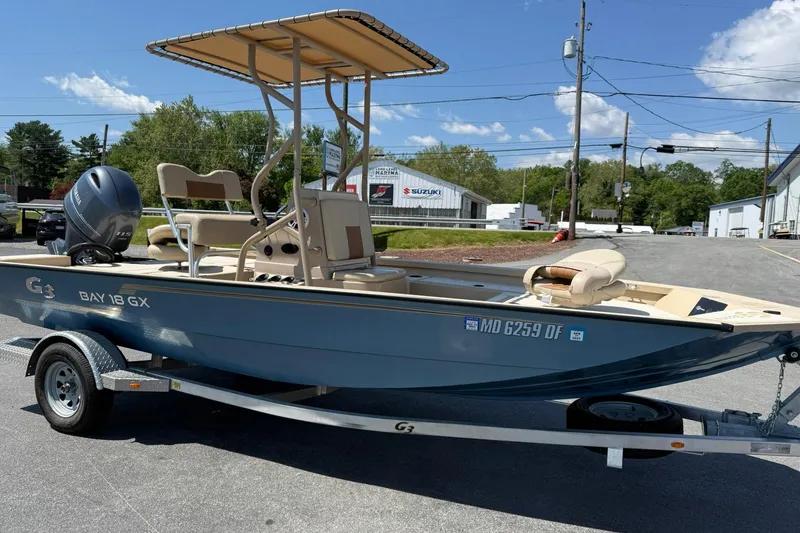 Slide: The Image of 2022 G3 Bay 18 GX boat on trailer, parked outdoors under clear sky. - 6