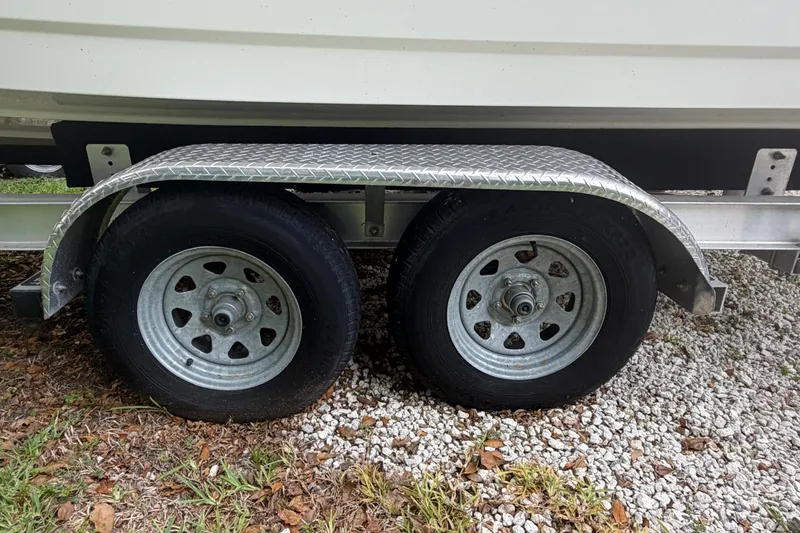 Slide: The Image of Trailer wheels of a 2019 Boston Whaler 210 Dauntless boat on gravel and grass. - 17