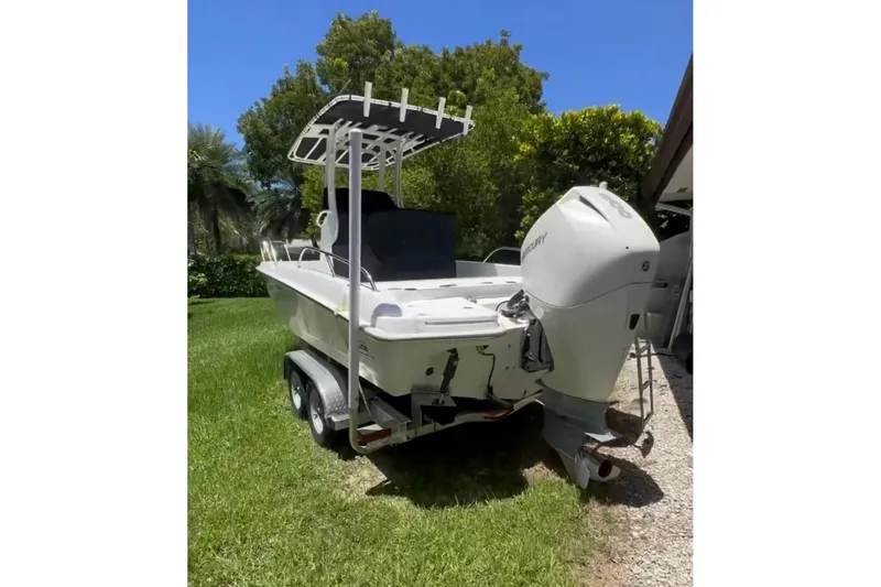 Slide: The Image of 2019 Boston Whaler 210 Dauntless boat on trailer, parked on grass under clear blue sky. - 4