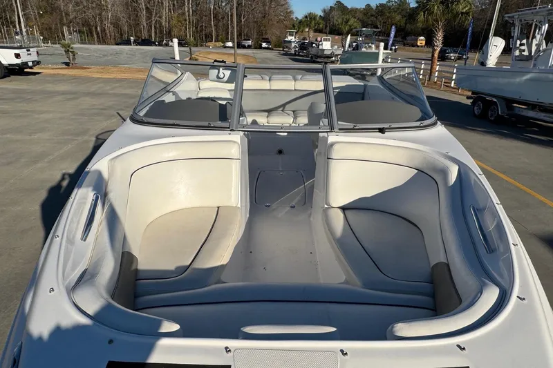 Slide: The Image of 2009 Hurricane SunDeck 210 IO boat with spacious seating and windshield, parked outdoors. - 10