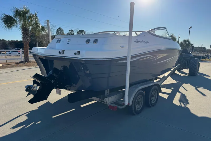 Slide: The Image of 2009 Hurricane SunDeck 210 IO boat on trailer, parked outdoors under clear sky. - 4