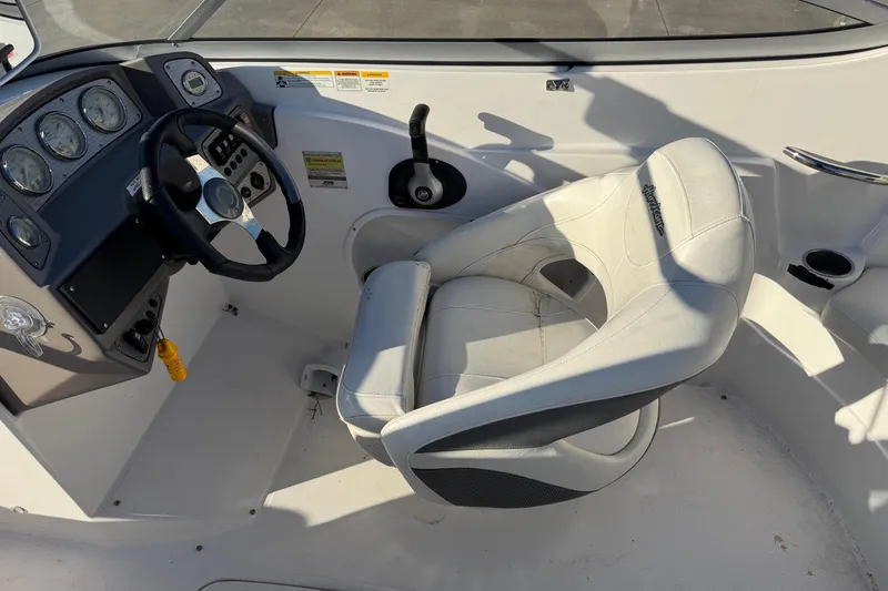 Slide: The Image of 2009 Hurricane SunDeck 210 IO boat cockpit with steering wheel and white captain's chair. - 9