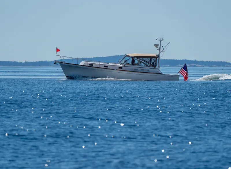 Slide: The Image of Grand Banks Eastbay 43 Ex 2000 cruising on a calm blue sea with American flag. - 11