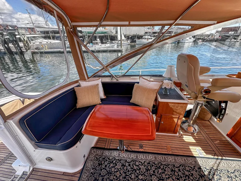 Slide: The Image of 2000 Grand Banks Eastbay 43 Ex cockpit with seating, table, and waterfront view. - 32