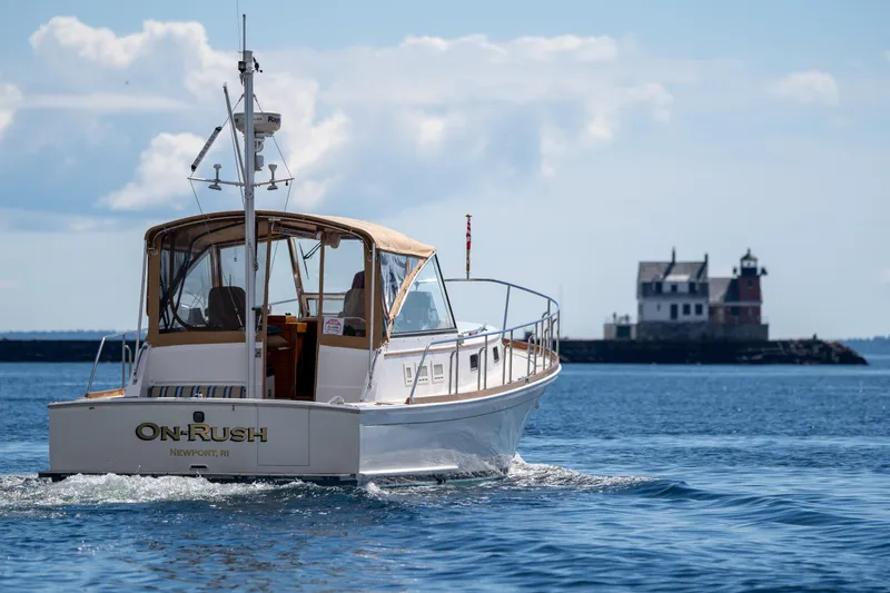 Slide: The Image of Grand Banks Eastbay 43 Ex 2000 boat cruising near a lighthouse on a sunny day. - 4