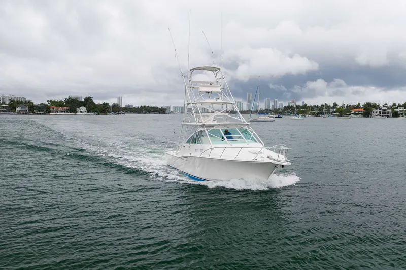 Slide: The Image of 2006 Cabo 35 Express yacht cruising on a cloudy day in a scenic waterway. - 12