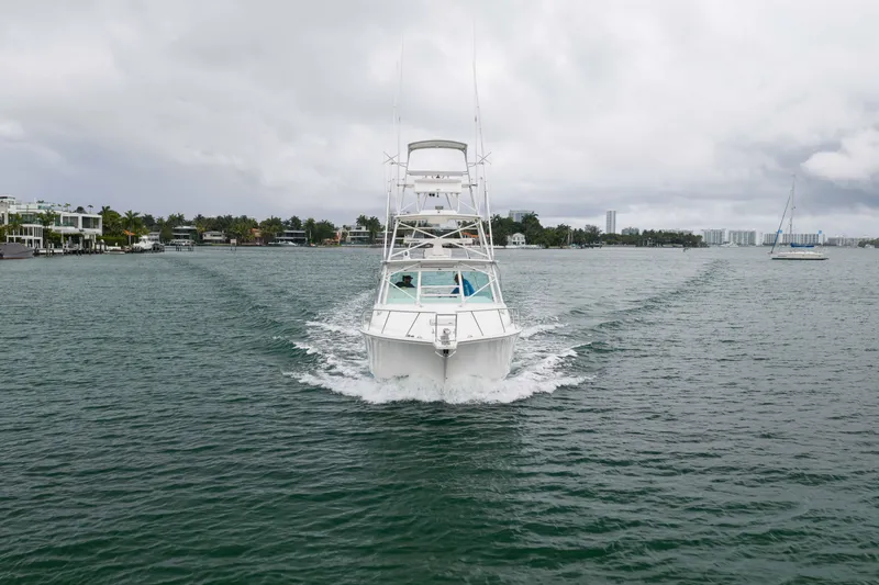 Slide: The Image of 2006 Cabo 35 Express boat cruising on a scenic waterway with cloudy skies. - 13
