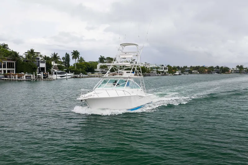 Slide: The Image of 2006 Cabo 35 Express yacht cruising on a scenic waterway with waterfront homes. - 14