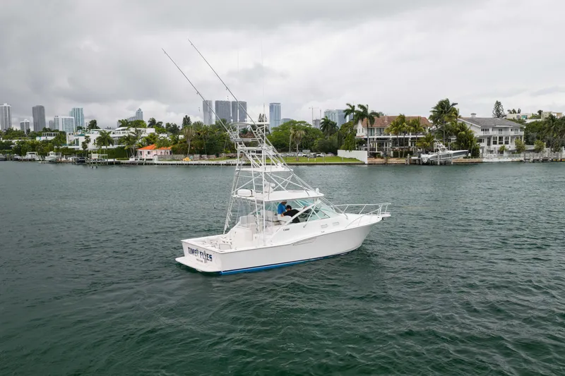 Slide: The Image of 2006 Cabo 35 Express boat cruising near waterfront homes under cloudy skies. - 3