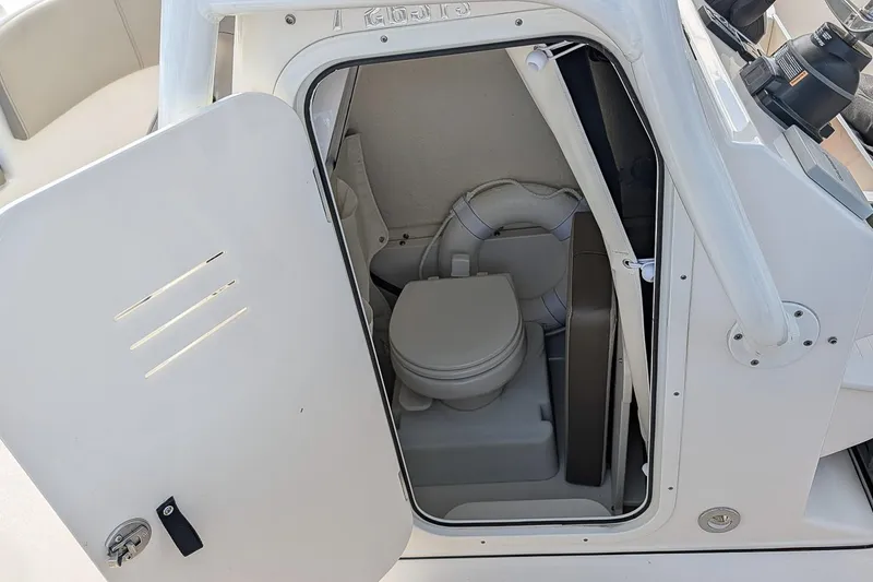 Slide: The Image of 2023 Key West 263 FS boat interior with open door revealing compact marine toilet. - 15