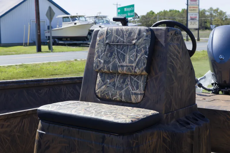 Slide: The Image of 2026 G3 Gator Tough 17 CC boat with camo seating and console, parked outdoors. - 11