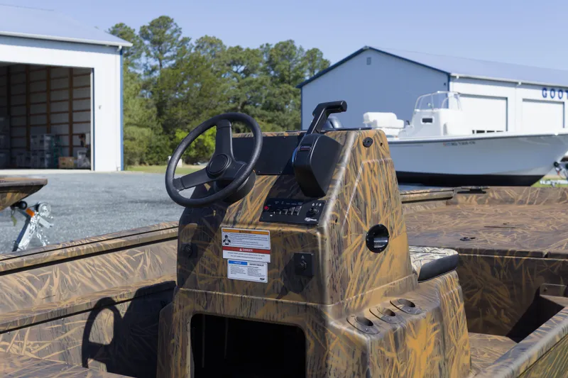 Slide: The Image of 2026 G3 Gator Tough 17 CC boat with camo design, parked near storage buildings. - 7