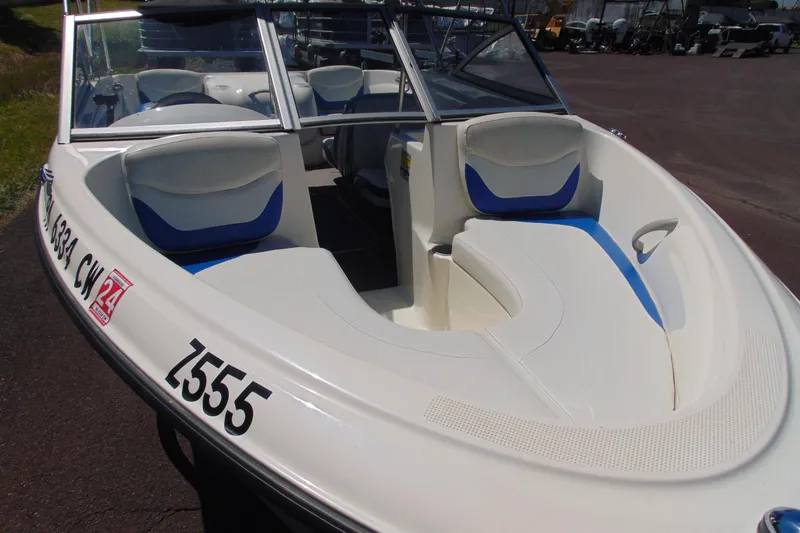 Slide: The Image of 2006 Bayliner 175 Bowrider boat with white and blue seating, docked outdoors. - 3
