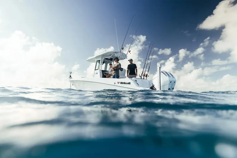 Slide: The Image of 2026 Wellcraft 243 Fisherman boat on open water, under a partly cloudy sky. - 2
