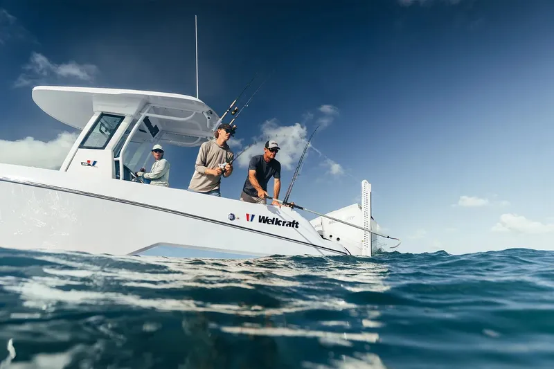 Slide: The Image of 2026 Wellcraft 243 Fisherman boat with anglers on open water under clear sky. - 3