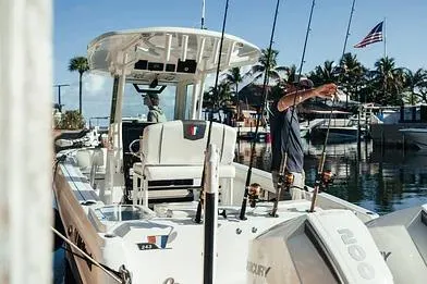 Slide: The Image of 2026 Wellcraft 243 Fisherman boat docked, equipped with fishing rods, palm trees in background. - 4