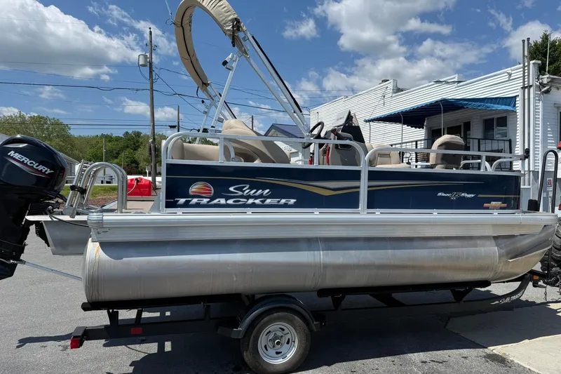 Slide: The Image of 2023 Sun Tracker Bass Buggy 16 XL Select pontoon boat on trailer, outdoor setting. - 5