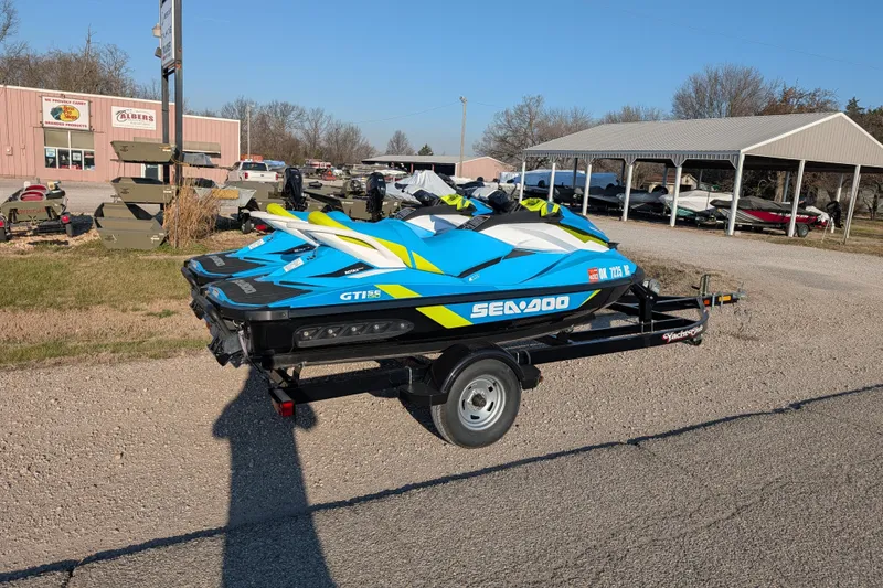 Slide: The Image of 2016 Sea-Doo GTI SE 130 jet skis on trailer in outdoor dealership lot. - 2