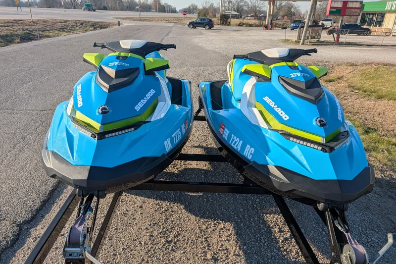 Slide: The Image of Two blue 2016 Sea-Doo GTI SE 130 jet skis on a trailer in a parking lot. - 3