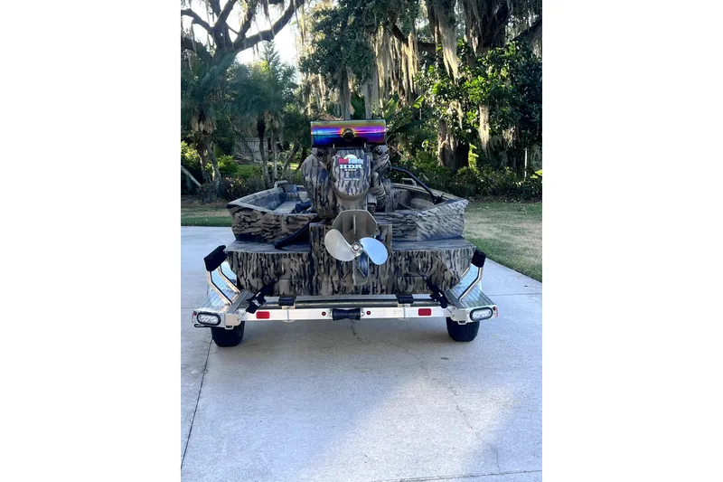 Slide: The Image of 2026 Excel 1854 Shallow Water F4 Pro Hull boat on trailer, camo design, outdoor setting. - 5