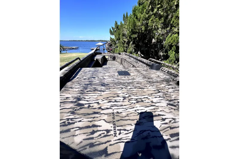 Slide: The Image of 2026 Excel 1854 Shallow Water F4 Pro Hull boat with camouflage design near a lake. - 8