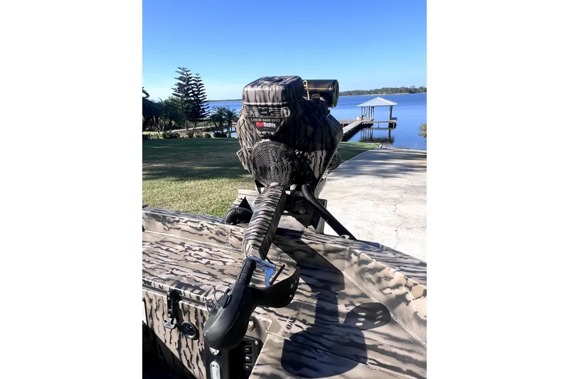 Slide: The Image of 2026 Excel 1854 Shallow Water F4 Pro Hull boat with camo design near a serene lake. - 9