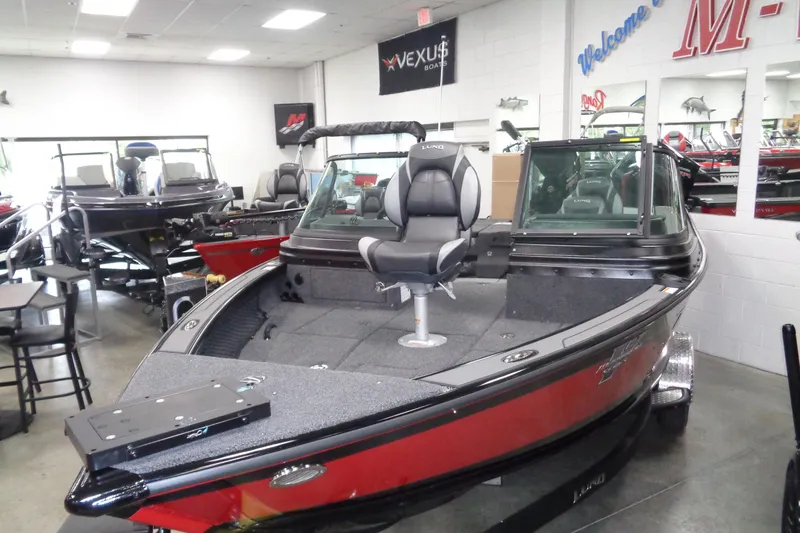 Slide: The Image of 2026 Lund 1875 Pro-V boat displayed in showroom, featuring sleek design and modern seating. - 12