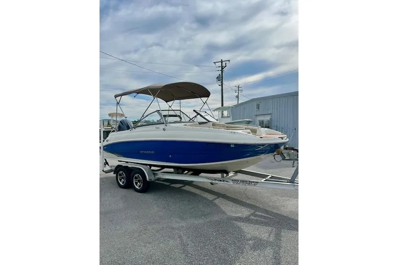 The Image of 2019 Stingray 201 DS boat on trailer, blue and white design, parked outdoors. - 1