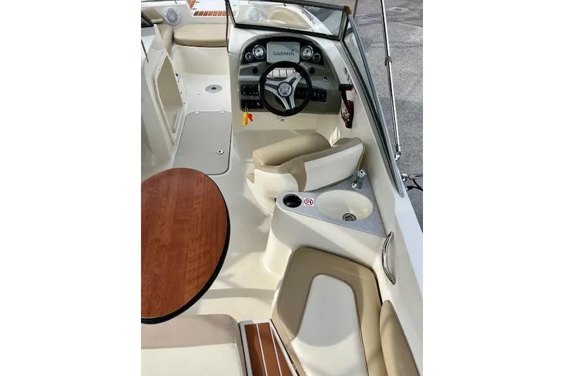 Slide: The Image of 2019 Stingray 201 DS boat interior with steering wheel, seating, and wooden table. - 6