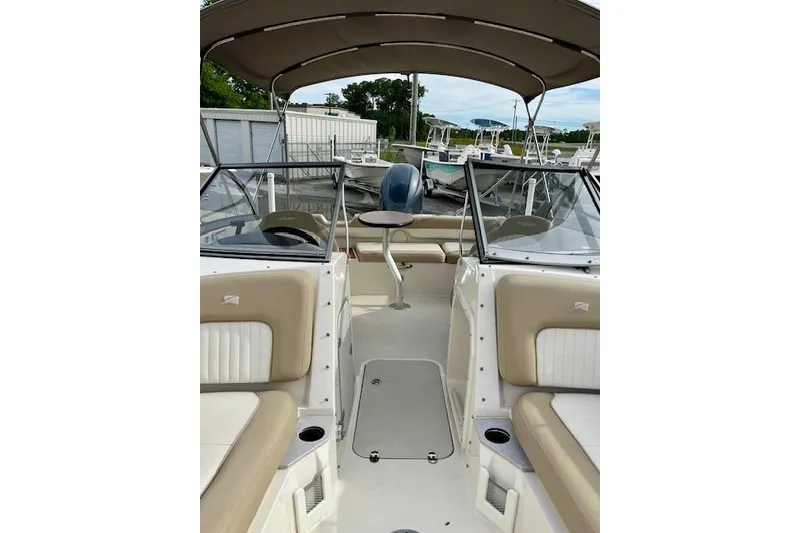 Slide: The Image of 2019 Stingray 201 DS boat interior with beige seating and canopy, docked at marina. - 9
