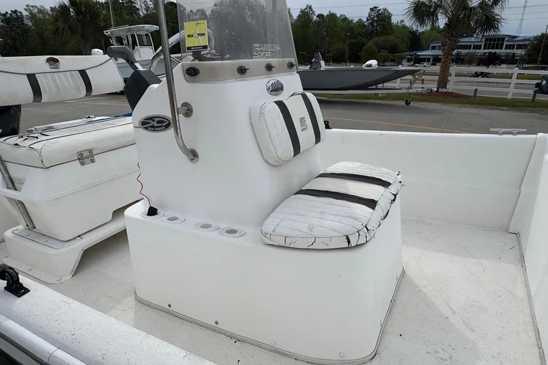 Slide: The Image of 2012 Carolina Skiff 1765 DLX boat interior with seating and console, parked outdoors. - 12