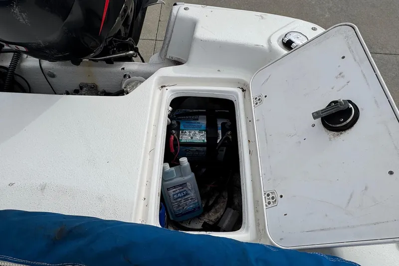 Slide: The Image of Open storage compartment on a 2012 Carolina Skiff 1765 DLX boat, showing battery and supplies. - 17
