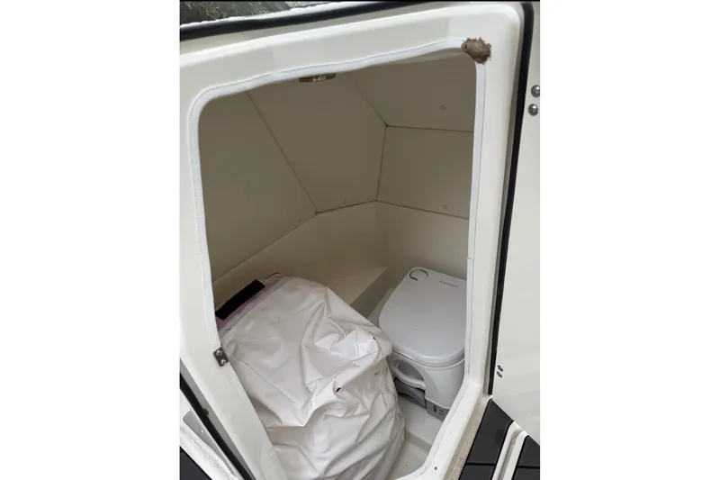 Slide: The Image of 2023 Bayliner DX 2200 boat interior with compact toilet and storage area. - 13