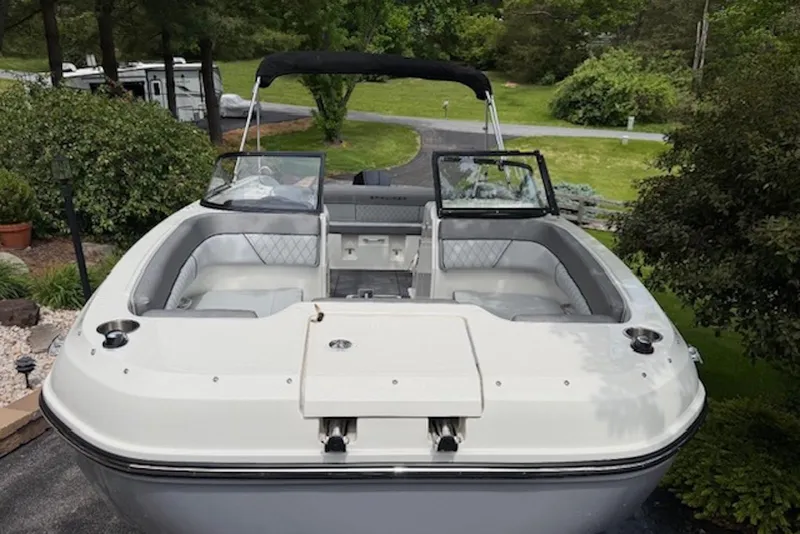 Slide: The Image of 2023 Bayliner DX 2200 boat with open seating, parked in a lush green setting. - 5