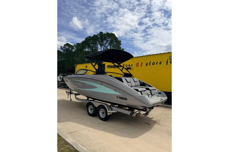 Slide: The Image of 2026 Yamaha Boats 255XD on trailer, parked outdoors under a partly cloudy sky. - 2