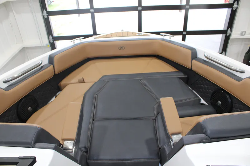 Slide: The Image of 2022 Cobalt R6 Surf boat interior with tan and black seating in a garage setting. - 12