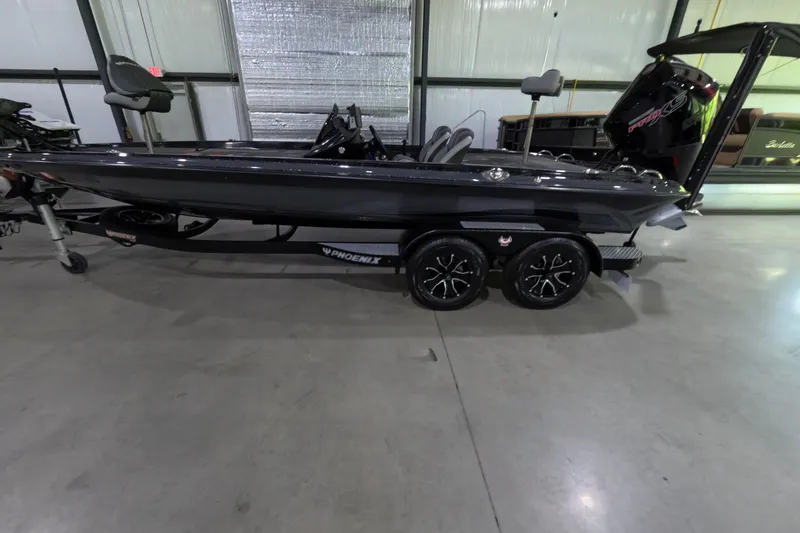 Slide: The Image of 2023 Phoenix 921 Elite boat in showroom, sleek design, black finish, dual axle trailer. - 8