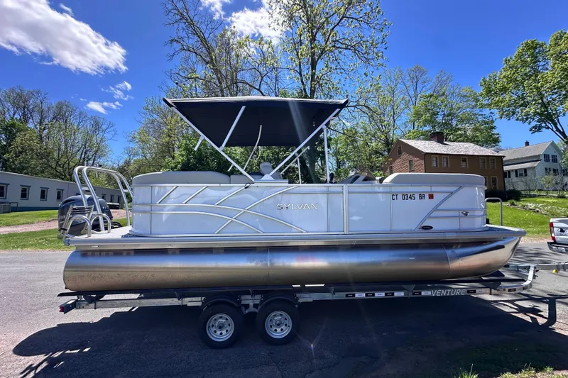 Slide: The Image of 2024 Sylvan Mirage 8522 LZ pontoon boat on trailer, parked outdoors. - 1