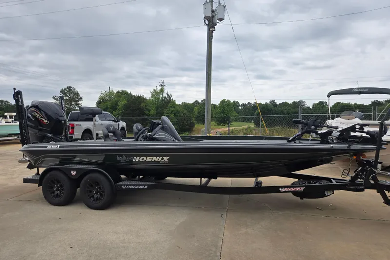 Slide: The Image of 2026 Phoenix 921 Elite X boat on trailer, parked outdoors under cloudy sky. - 2